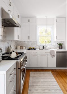 a kitchen with white cabinets and stainless steel appliances