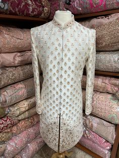 Beige cream raw silk sherwani blooms with fine floral jaal pattern charmed with resham thread and highlighted in gold stone and pearl embroidery. Available with matching chudidar. Size: 40/M Occasion: Wedding Ceremony or Reception WASH CARE INSTRUCTIONS - Please Dry clean only when it is applicable. Slight color variation is possible due to digital photography. Ready to Ship! Ceremonial Clothing, Pearl Embroidery, Gold Stone, Extra Fabric, Churidar, Sherwani, Raw Silk, Digital Photography, Shoulder Sleeve