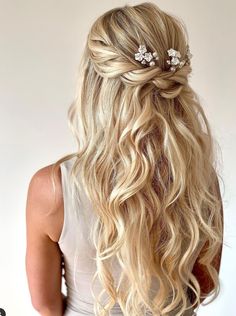 a woman with long blonde hair wearing a white dress and two flower clips in her hair