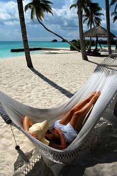 a woman laying in a hammock on the beach