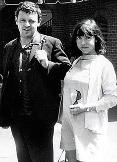 two people standing next to each other in front of a building with the word love written on it