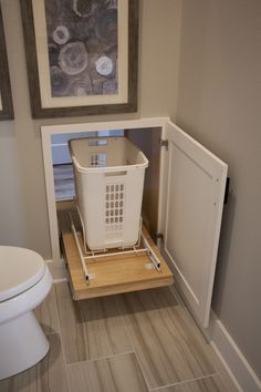 a white trash can sitting on top of a wooden shelf in the corner of a bathroom