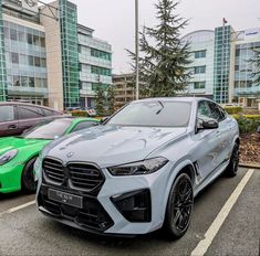 two cars parked in a parking lot next to each other with buildings in the background