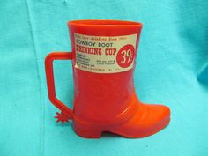 an orange cowboy boot drinking cup sitting on top of a blue cloth