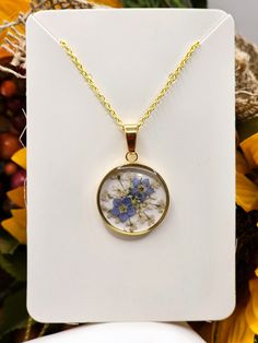 a necklace with flowers on it sitting in front of a white card and yellow flowers