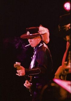 a man wearing a cowboy hat and holding a cell phone in his hand while standing on stage