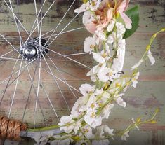 a bicycle wheel with flowers on it and a rope tied around the spokes that are attached