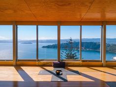 a yoga room with large windows looking out at the water and mountains in the distance