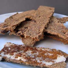 several pieces of brownie on a white plate with cream and cinnamon sprinkles