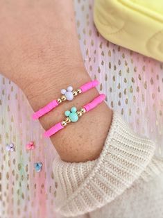 a person wearing two bracelets on their wrist with beads and charms around the wrist