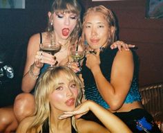 three beautiful young women sitting next to each other holding wine glasses and posing for the camera