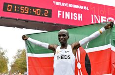 a man holding his arms up in front of a kenya flag and a score board