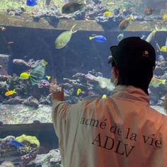 a man standing in front of an aquarium looking at fish