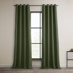 a green curtain hanging in front of a window with a white wall and wooden floor