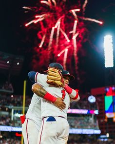 two baseball players hugging each other with fireworks in the background