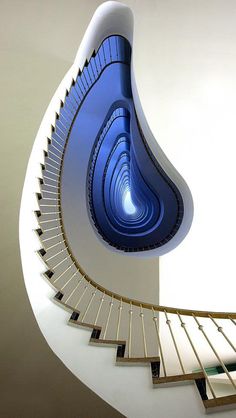 a spiral staircase with blue light coming from the top and bottom, in a white room