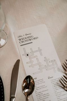 a crossword puzzle on a table next to silverware and wine glasses with utensils