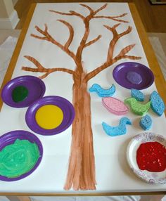 an art project with paper plates and paint on the table, including a painted tree