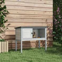 a small dog house in the grass next to a fence