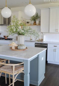 a kitchen with white cabinets and marble counter tops, two chairs at the center island