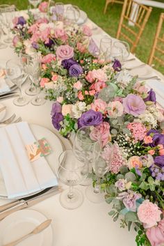 a long table is set with flowers and place settings for an elegant wedding reception at the park