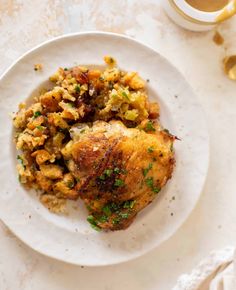 a white plate topped with chicken and stuffing next to a cup of tea on a table