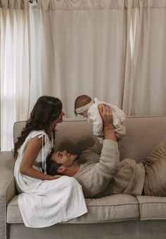 a man and woman laying on a couch with a baby