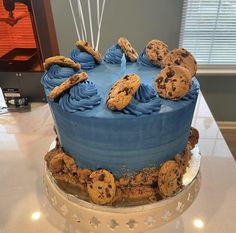 a blue frosted cake with cookies and chocolate chip cookies on the top is sitting on a table