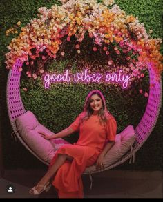 a woman sitting on a chair in front of a flower wall with the words good vibes only