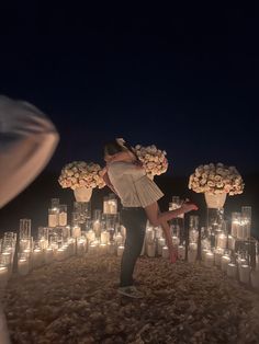 a man and woman kissing in front of many lit up candles on the ground at night