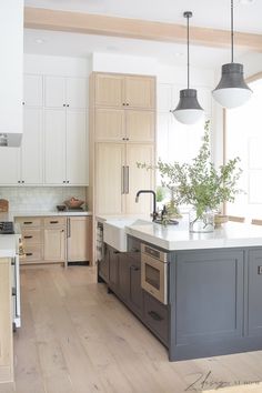 a large kitchen with an island in the middle and two pendant lights hanging from the ceiling