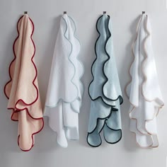 three towels hanging on the wall next to each other with scalloped edges in different colors