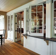 the inside of a house with wood floors and white doors, windows, and table