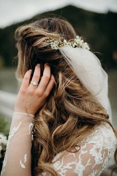 a woman with long hair wearing a veil and holding her hand up to her face