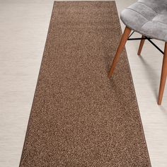 a brown rug on the floor next to a gray chair and grey chair with wooden legs