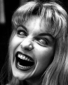 a black and white photo of a woman with an evil look on her face smiling