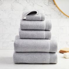 towels stacked on top of each other in front of a bathroom mirror and marble wall