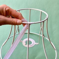 a hand holding a white ribbon over a wire basket