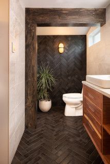 a bathroom with a toilet, sink and wood cabinetry in it's center