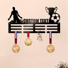 there are medals hanging on the wall next to two keys and a medal holder with a soccer trophy