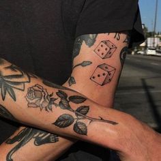 two people with tattoos on their arms holding onto each other's hands, one has dice and the other has roses