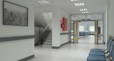 an empty hospital hallway with blue chairs and pictures on the wall