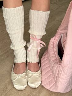 a woman's feet in white shoes next to a pink purse