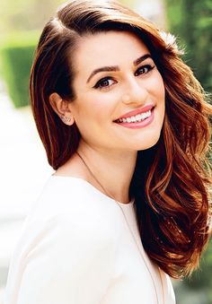 an image of a woman with long hair smiling at the camera and wearing a white top