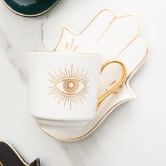 a white and gold coffee cup with an eye on it