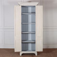 a tall white cabinet sitting on top of a wooden floor