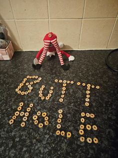 an elf sitting on the floor next to a sign that says joy spelled out in gold letters