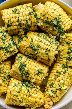 grilled corn on the cob with parsley in a white bowl, ready to be eaten