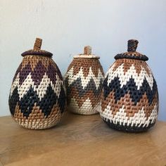 three woven baskets sitting on top of a wooden table