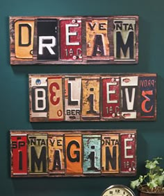 three wooden signs are hanging on the wall next to a clock and potted plant